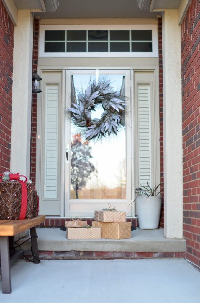 wrapped packages on the doorstep of a home decorated for Christmas