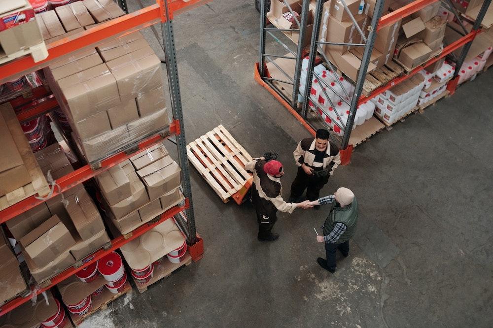 three people shaking hands in warehouse